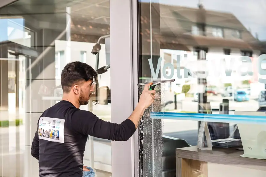 Mitarbeiter von SuperCleanup zieht eine Schaufensterscheibe mit dem Abzieher ab
